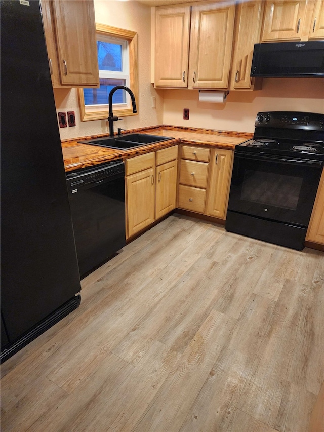 kitchen featuring butcher block counters, a sink, light wood-style floors, range hood, and black appliances