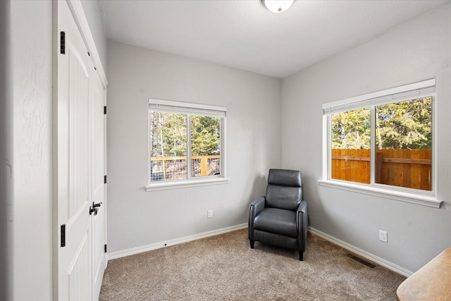 living area with carpet floors, a wealth of natural light, visible vents, and baseboards