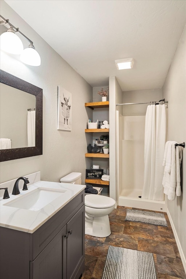 bathroom with toilet, a stall shower, baseboards, and vanity