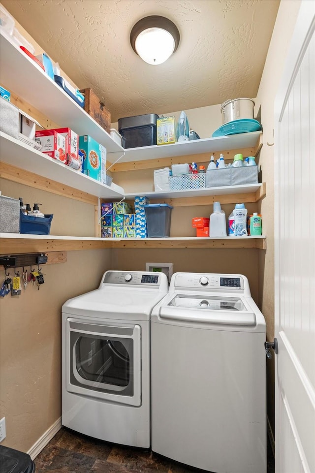 clothes washing area with laundry area, washer and clothes dryer, stone finish floor, and baseboards