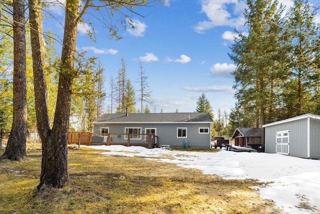 snow covered rear of property with a storage unit, an outdoor structure, and a wooden deck