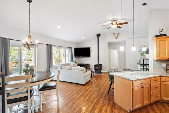 kitchen with light stone counters, dark wood-style flooring, backsplash, a wood stove, and vaulted ceiling