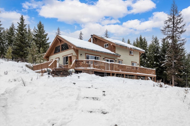 snow covered back of property with a deck