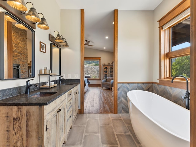 full bathroom with plenty of natural light, connected bathroom, and a sink