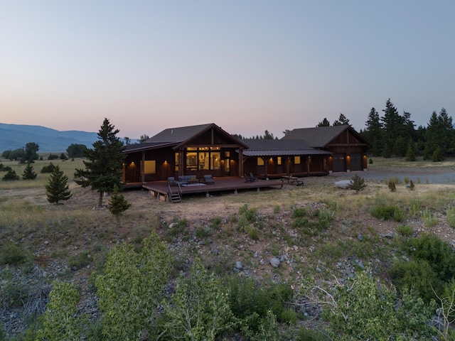 back of property at dusk with a garage, driveway, and a deck