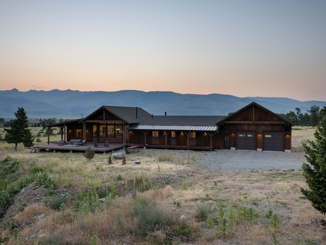 view of front of house with metal roof, an attached garage, a mountain view, a standing seam roof, and gravel driveway