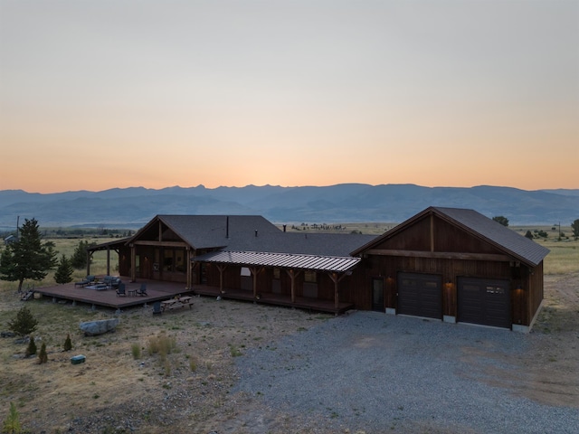 view of front of home featuring driveway, a standing seam roof, a deck with mountain view, and metal roof