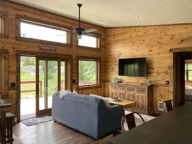 living area with wood walls, wood ceiling, a ceiling fan, and wood finished floors