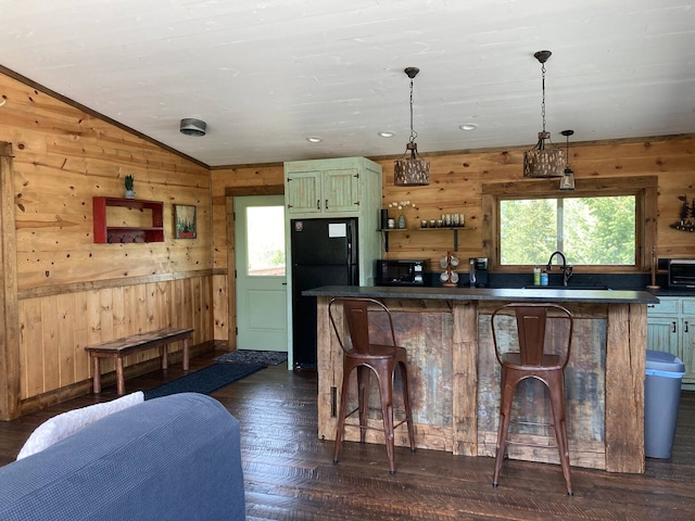 kitchen with a wealth of natural light, a sink, wood walls, and black appliances