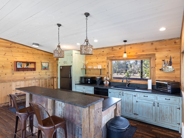 kitchen with dark countertops, a kitchen island, dark wood-style flooring, black appliances, and a sink