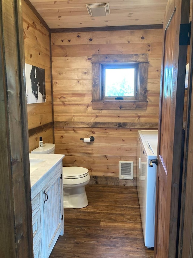 half bathroom with visible vents, toilet, wood finished floors, washer and dryer, and wooden ceiling