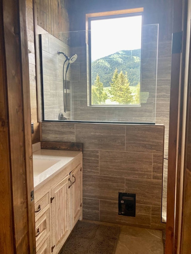 full bathroom with a tile shower and vanity