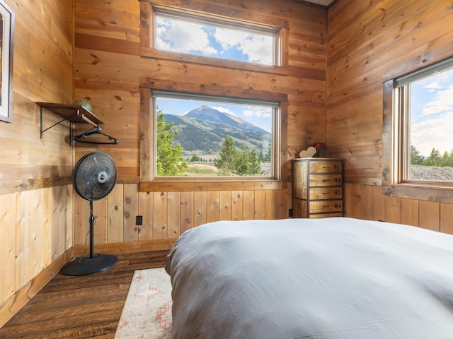 bedroom with wood walls, multiple windows, a mountain view, and wood finished floors