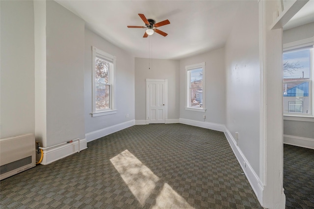 carpeted empty room featuring heating unit, a ceiling fan, and baseboards