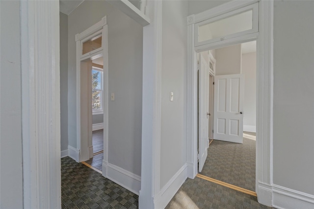 hall with dark carpet and baseboards