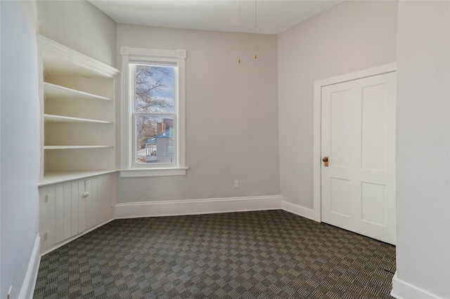 empty room with dark colored carpet and baseboards