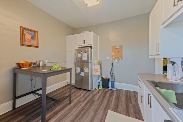 kitchen featuring dark wood-type flooring, freestanding refrigerator, white cabinetry, a sink, and baseboards