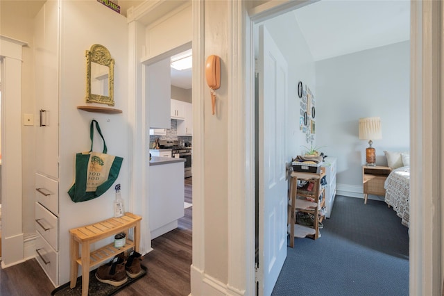 hallway featuring dark wood-type flooring and baseboards