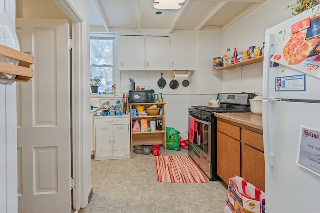 kitchen featuring white cabinets, gas range, freestanding refrigerator, black microwave, and open shelves