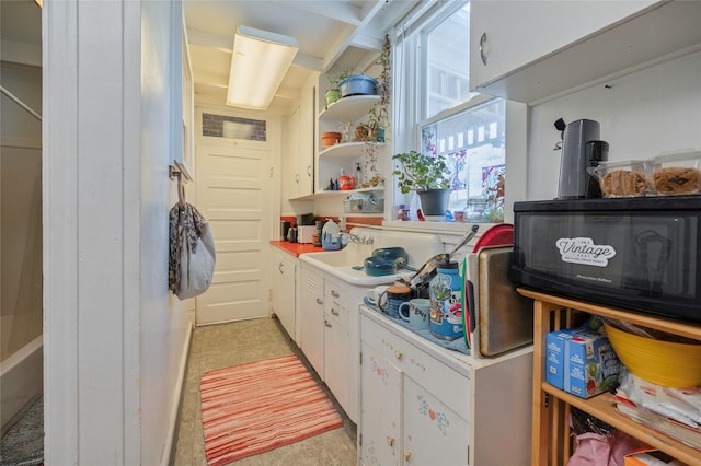 kitchen featuring light countertops, open shelves, and white cabinetry