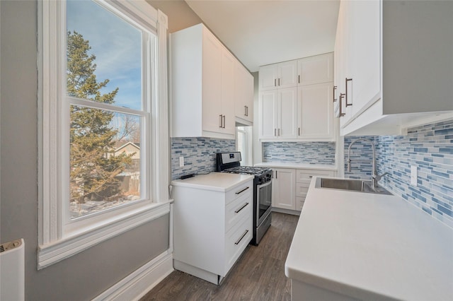 kitchen featuring a sink, white cabinetry, light countertops, stainless steel gas range, and dark wood-style floors