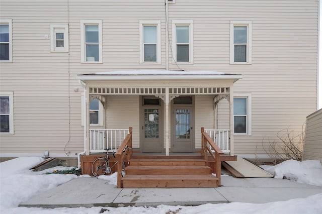 snow covered property entrance with covered porch