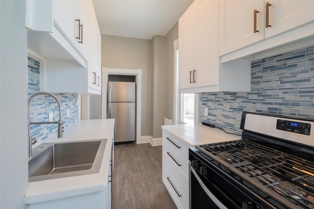 kitchen with white cabinets, appliances with stainless steel finishes, dark wood-style flooring, light countertops, and a sink