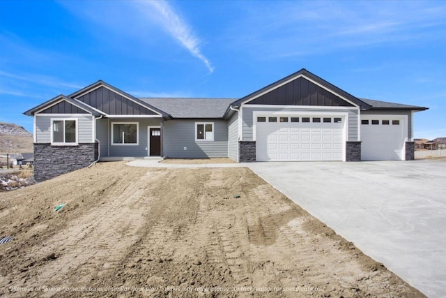 view of front of property featuring stone siding, concrete driveway, board and batten siding, and an attached garage