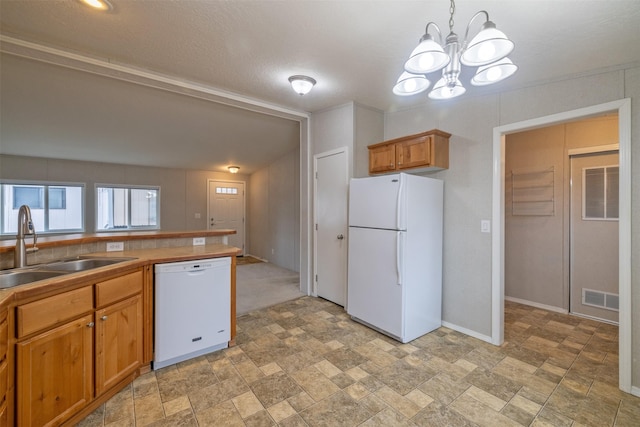 kitchen featuring white appliances, a sink, visible vents, brown cabinets, and stone finish floor