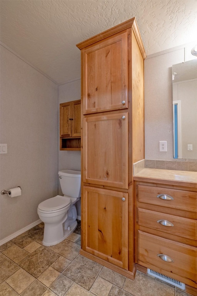 bathroom featuring toilet, baseboards, a textured ceiling, and vanity