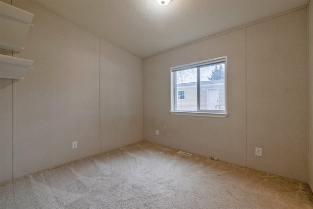 spare room with lofted ceiling, a textured ceiling, carpet, and visible vents