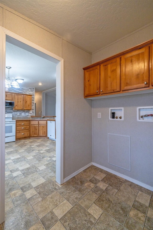 laundry area featuring a textured ceiling, washer hookup, cabinet space, and baseboards