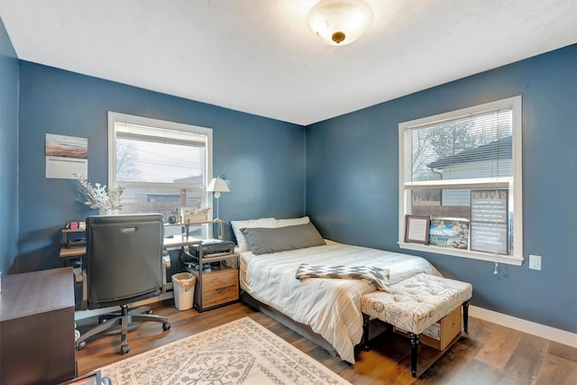 bedroom with multiple windows, wood finished floors, and baseboards