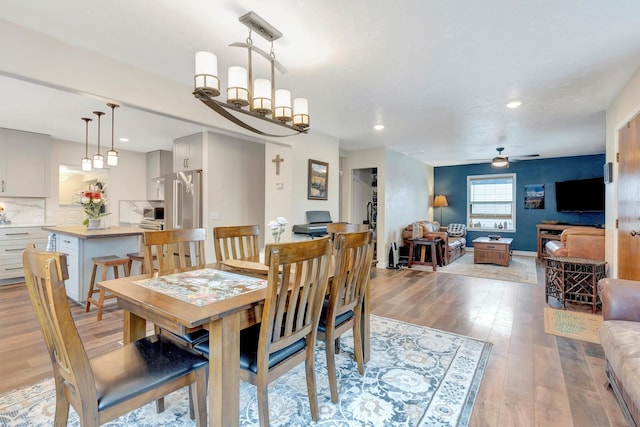 dining space with recessed lighting, light wood-style flooring, baseboards, and ceiling fan with notable chandelier