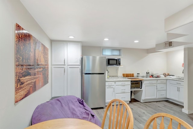 kitchen with recessed lighting, light countertops, appliances with stainless steel finishes, light wood-style floors, and white cabinets