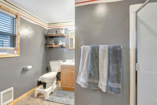 bathroom with baseboards, visible vents, toilet, a shower with door, and vanity