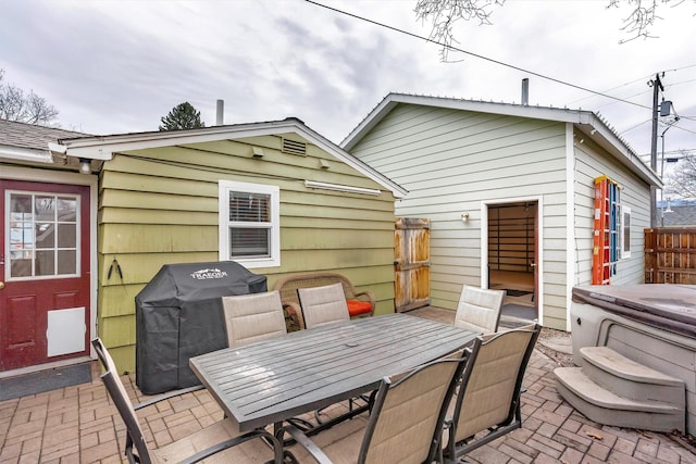 view of patio / terrace with outdoor dining area, fence, a grill, and a hot tub