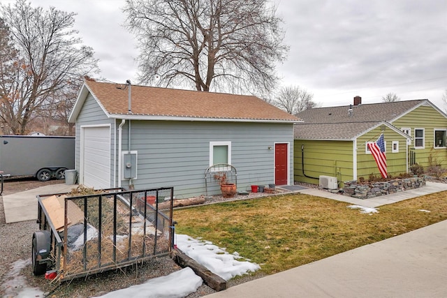 back of house with an outbuilding, a yard, a shingled roof, and a detached garage