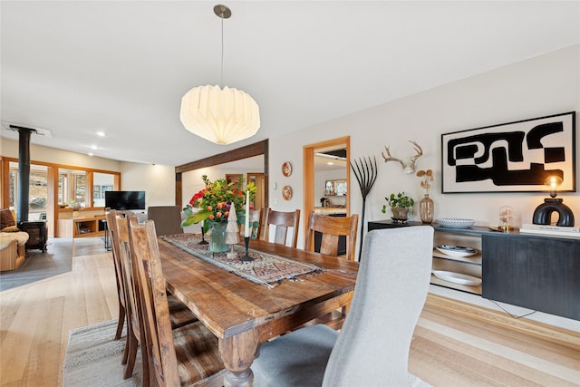 dining room with light wood finished floors and a wood stove