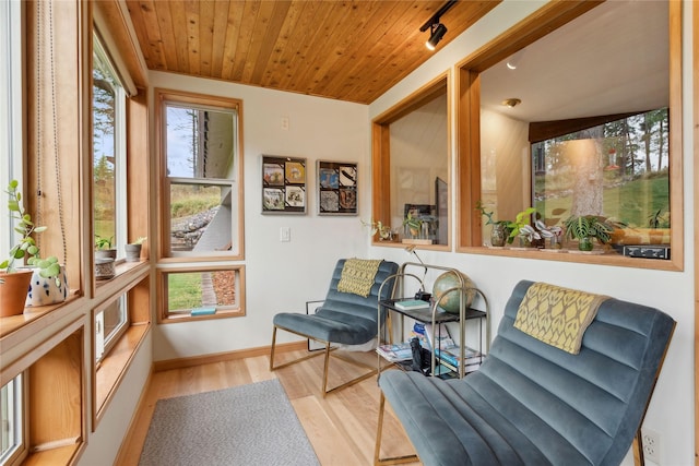 living area featuring wood ceiling, baseboards, and wood finished floors