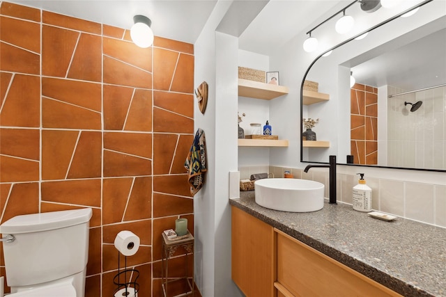 bathroom featuring vanity, tile walls, toilet, and tiled shower