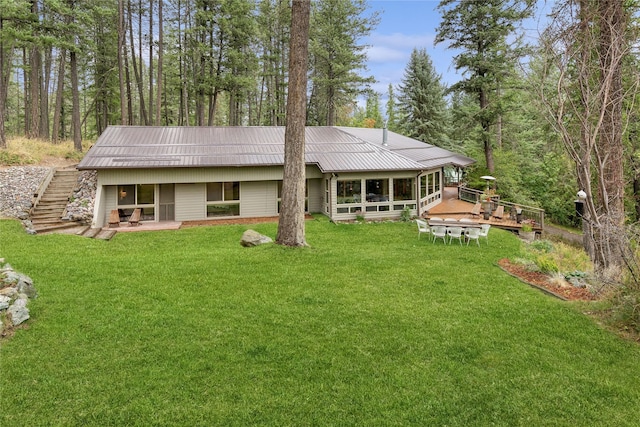 back of property featuring a wooden deck, stairway, a lawn, and metal roof