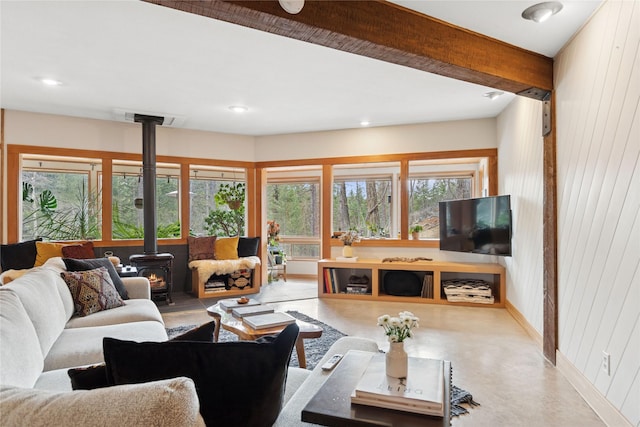 living room featuring wooden walls, visible vents, baseboards, a wood stove, and recessed lighting