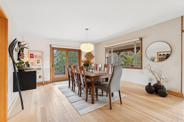 dining area with light wood-type flooring, baseboards, and a healthy amount of sunlight