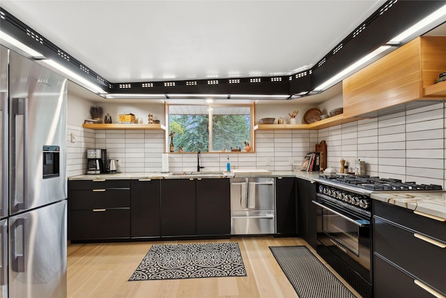 kitchen with dark cabinetry, open shelves, stainless steel fridge with ice dispenser, a sink, and high end black range oven