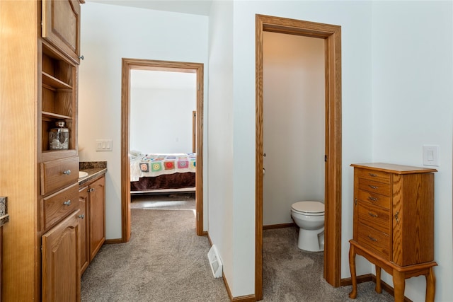 bathroom featuring connected bathroom, toilet, carpet flooring, vanity, and baseboards