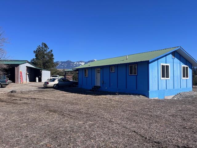 116 Happy Holw, Eureka, MT 59917 - view of front of property featuring board and batten siding, a mountain view, an outbuilding, and a metal roof