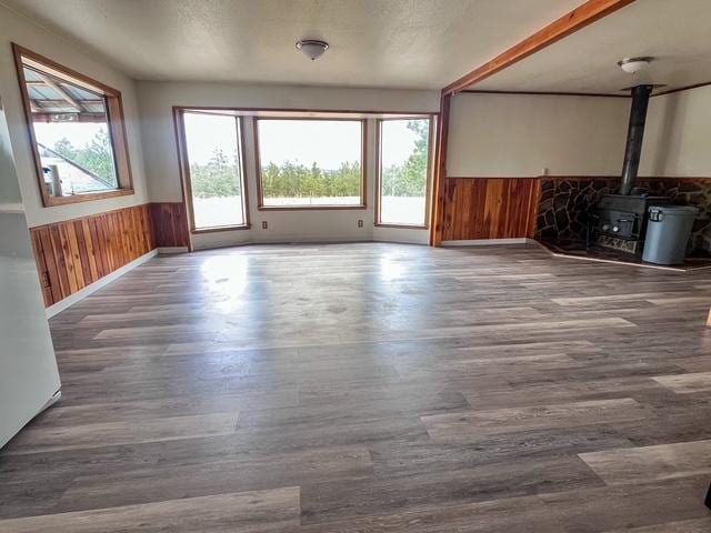 116 Happy Holw, Eureka, MT 59917 - unfurnished living room with a wainscoted wall, wood finished floors, a wood stove, and wooden walls