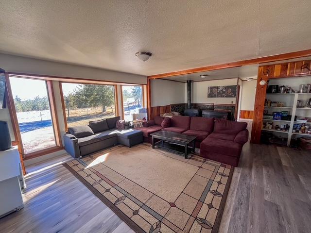 living room featuring a wood stove, a textured ceiling, wood finished floors, and wainscoting