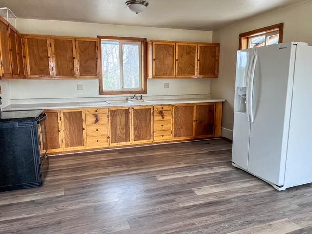 116 Happy Holw, Eureka, MT 59917 - kitchen featuring white refrigerator with ice dispenser, range, brown cabinetry, dark wood finished floors, and light countertops
